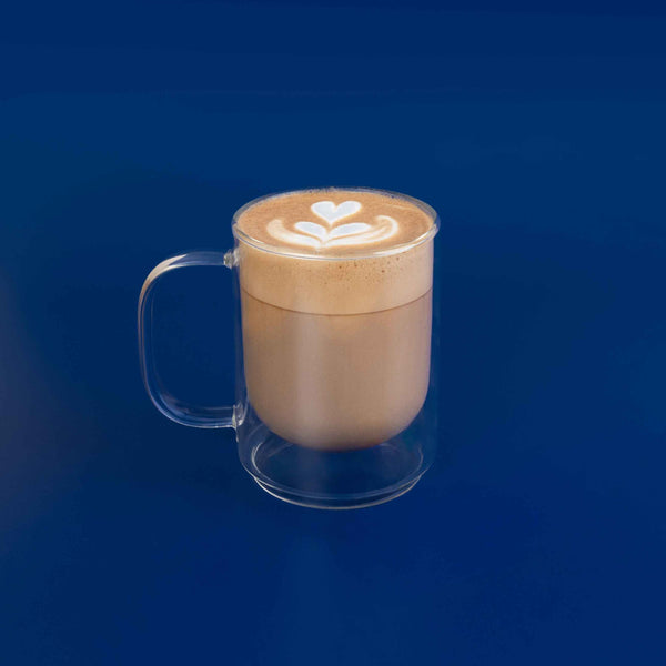Clear mug with a latte art design on a blue background