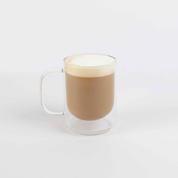 Clear glass mug with a hot beverage on a white background