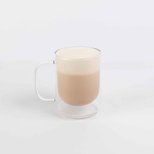 Clear glass mug with a handle filled with a creamy beverage on a white background
