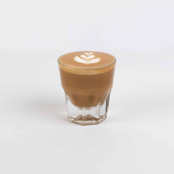 Glass of coffee with latte art on a white background