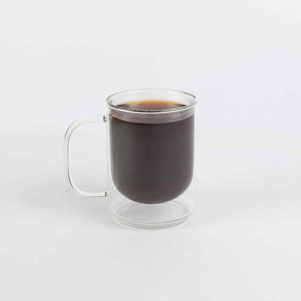 Clear glass mug with handle filled with black coffee on a white background