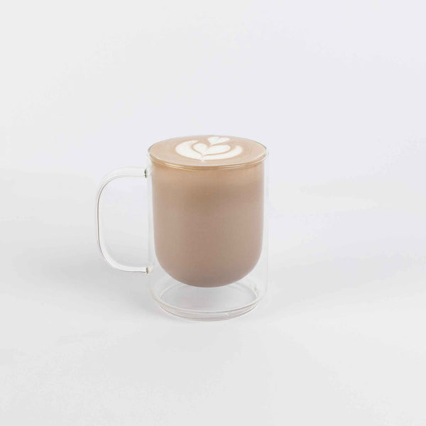 Glass mug with a creamy beverage on a white background