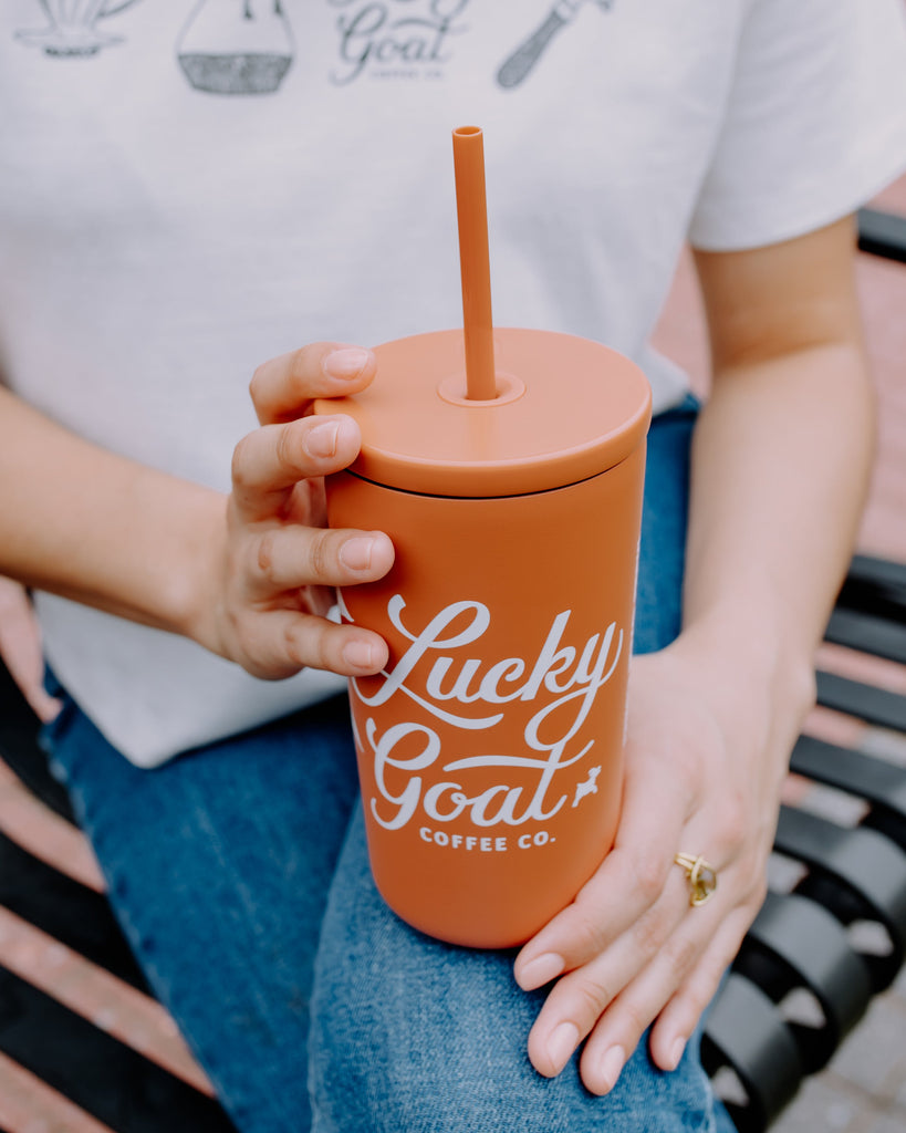 terracotta cold cup with coffee plant Lucky Goat logo and straw lid.