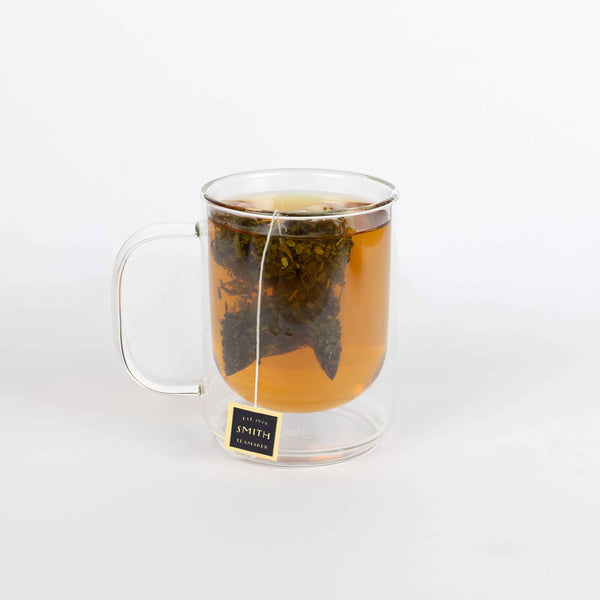 Clear glass mug with tea bag steeping in a white background